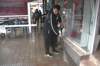 Pla sencer d'un comerciant de la plaça González Isla netejant el fang que ha portat el temporal.