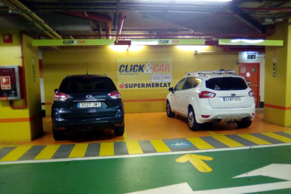 Los propietarios de dos vehículos esperan la llegada del pedido encargado a la zona habilitada para el servicio 'click&car'.