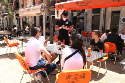 Plano abierto de un camarero anotando la comada a unos clientes en una terraza de la plaza de la Font de Tarragona en el primer sábado de la fase 1.