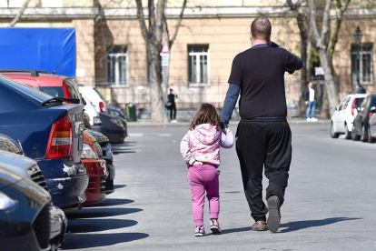 Un padre acompaña a su hija por la calle.