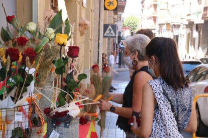 Dos jóvenes comprando rosas en la Floristería Tost de Tortosa durante el Sant Jordi de verano.