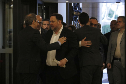 Quim Torra y Oriol Junqueras saludándose con Josep Rull y Roger Torrent abrazándose al lado, a la entrada del Parlament.