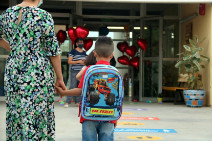 Un niño de la mano de su madre llegando a una escuela.