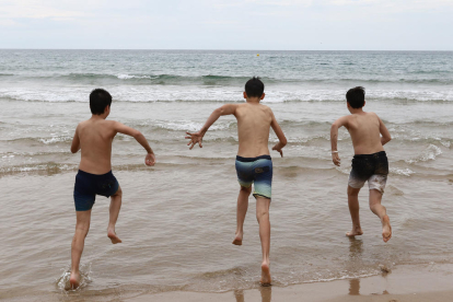 Tres jóvenes se adentran en el mar en una playa de Tarragona.