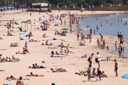 La platja de l'Arrabassada de Tarragona, amb banyistes i gent prenent el sol.
