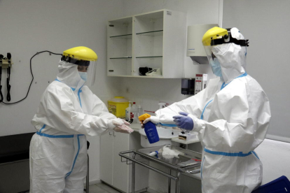 Professionals d'un CAP de Girona desinfectant els guants després d'extreure mostres per a la prova PCR.