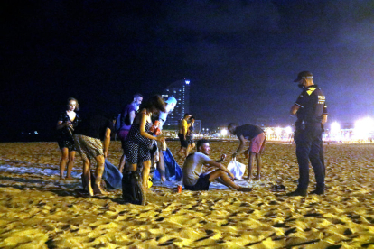 Un grupo de personas que hacía botellón en la playa de la Barceloneta ante la presencia de la Guardia Urbana.
