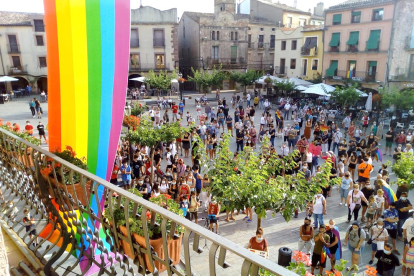 La plaza Major de Prades llena de personas concentradas contra la homofobia, con la bandera LGTBI colgada en primer término en el Ayuntamiento.