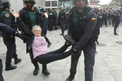 Una abuela es llevada en brazos por agentes de la Guardia Civil en el desalojo del colegio electoral de la Ràpita.