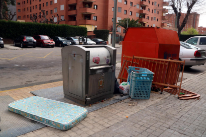 Un contenedor soterrado de Tarragona con diversos voluminosos cerca, como un colchón y una cuna medio desmontada.