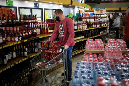 Un home comprant alcohol en un supermercat.
