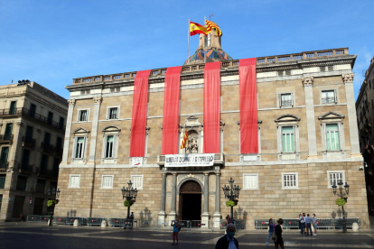 Fachada principal del Palau de la Generalitat con cuatro grandes lonas verticales rojas como las cuatro barras para conmemorar el 1-O.