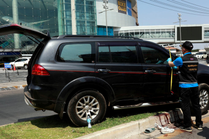 Un policia tailandès inspecciona el vehicle d'una de les víctimes del tiroteig