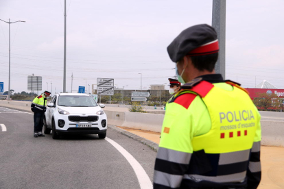 Un agent dels Mossos d'Esquadra en primer terme i un vehicle al control policial de la T-11 a Tarragona.