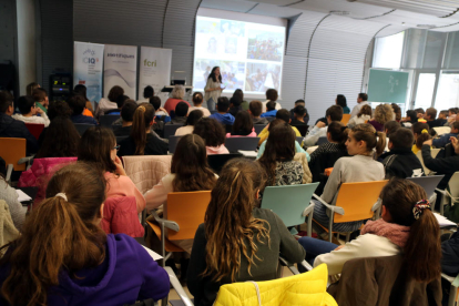 Tres niñas, de espaldas, siguiendo una de las charlas de la iniciativa '100tífiques' en la sede del ICIQ en Tarragona.