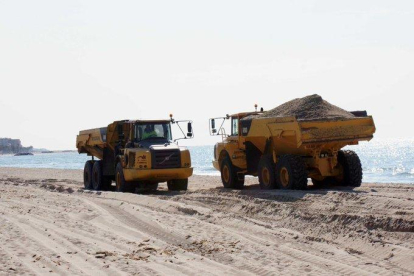 Dos camiones aportando arena en la playa de Calafell.
