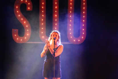 La cantante Suu con el nombre del grupo de fondo durante su concierto en el Festival Acústica de Figueres el 29 de agosto de 2019.