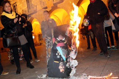 Una mujer fotografía como arde una imagen de Felipe VI.