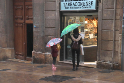 Una mujer y una niña, a punto de entrar en una pastelería de la calle Comte de Rius de Tarragona.