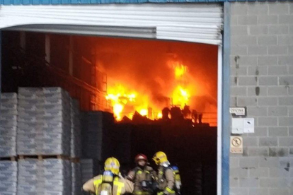 Els bombers treballant a l'interior de la fàbrica on va originar-se l'incendi.