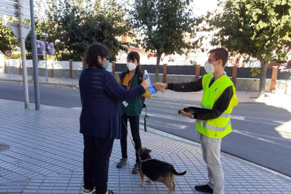 Dos agentes cívicos informando a una mujer con su perro.