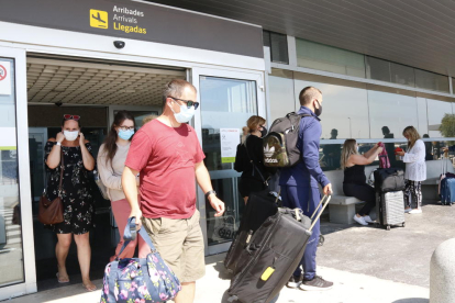Plano general de turistas con maletas, en la terminal de llegadas del aeropuerto de Reus.