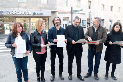 Els representants polítics del Camp de Tarragona amb la proposta de resolució que presentaran al Parlament, evidenciant la unitat davant l'estació de tren de Tarragona.