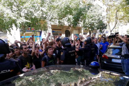 La policia espanyola envoltant la seu de la CUP, mentre simpatitzants criden en contra de l'actuació i en favor de l'1-O, el 20 de setembre de 2017.