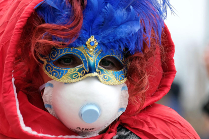 Una persona con la máscara de Carnaval y una mascarilla de papel por el coronavirus en Venecia