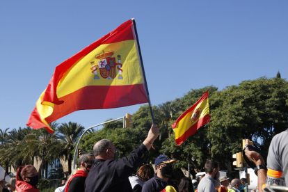 Unos manifestantes alzando banderas españolas durante la concentración en el monumento a Cristòfor Colom