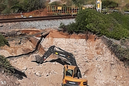 Una excavadora trabaja para reparar un boquete en el tramo Vilanova-Sitges de la línea de Rodalies de Renfe R2 sur.