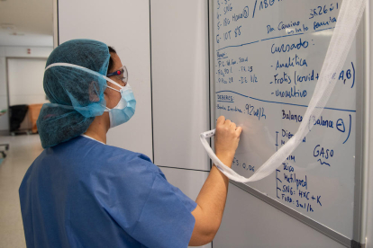 Una profesional sanitaria coge notas en una pizarra de los tratamientos y pruebas a los pacientes con covid-19 en uno de los bloques quirúrgicos del Hospital Clínic de Barcelona habilitado como UCI en la pandemia de coronavirus.