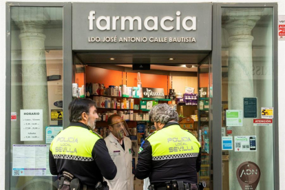 Dos agents de la policia local de Sevilla a l'entrada d'una farmàcia.