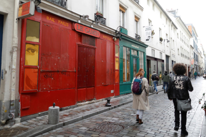 Diverses persones caminen davant d'un bar tancat per les restriccions de la covid-19 a París.