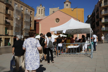 Una cola de personas en un punto de distribución de agua bendecida de Sant Magí, en un espacio habilitado en la Part Alta.