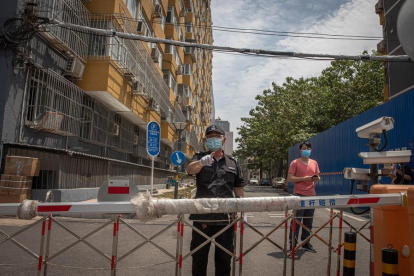 Una persona de seguretat vigila un complex residencial tancat prop del mercat de Yuquandong, al districte de Haidian, Pequín.