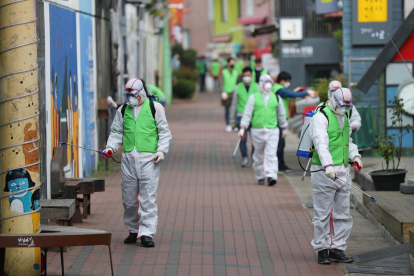 Treballadors desinfecten un carrer a Corea del Sur