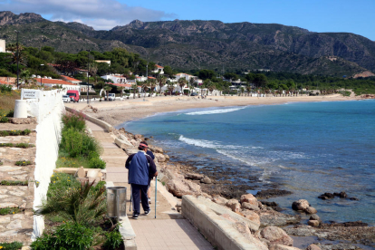 Pla general de dues persones que passegen en direcció a la platja de l'Almadrava, al municipi de Vandellòs i l'Hospitalet de l'Infant.