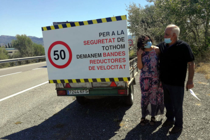 Dos de los vecinos de la nueva plataforma de Ascó al lado del cartel reivindicativo para pedir mejoras en seguridad viaria en la C-12.