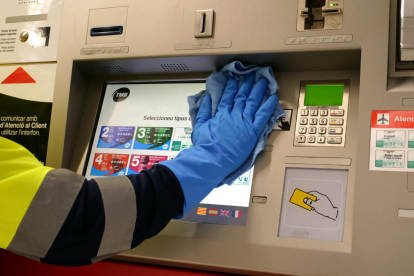 Un treballador de TMB neteja una màquina de venda de bitllets.