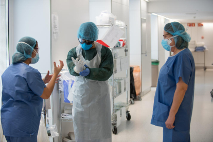 Dues professionals sanitàries ajuden una companya a protegir-se abans d'atendre un pacient amb covid-19.