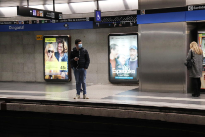 Un home amb mascareta esperant el metro a l'andana de l'estació de Diagonal de Barcelona.