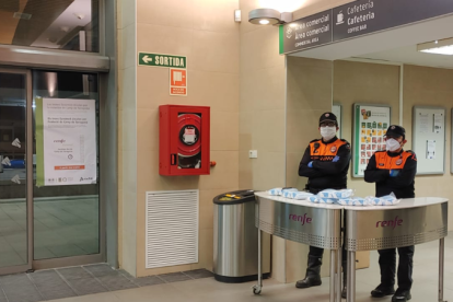 Dos miembros de Protección Civil a punto para repartir mascarillas en la estación de tren de Tarragona