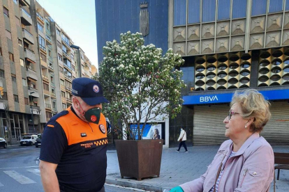 Un membre de Protecció Civil donant una mascareta a una dona a l'autobusos de Tarragona.