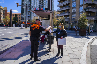 Un voluntari de Protecció Civil entregant una mascareta a una usuària de l'EMT a la parada de la plaça Imperial Tàrraco.