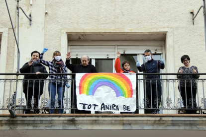 D'alguns dels usuaris i personal de la residència ca n'Aleix de l'associació Alba saludant des del balcó on hi ha penjat un cartell amb el lema 