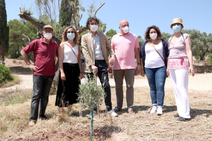 El alcalde de Flix, Francesc Barbero, acompañado de concejales, delante del olivo que han plantado en el acto de conmemoración del primer aniversario del incendio de la Ribera de Ebro.