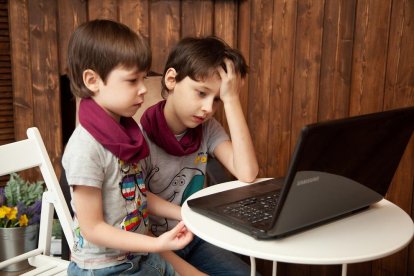 Dos nens davant un ordinador portàtil.
