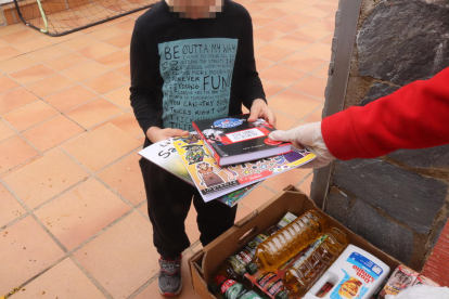 Pla mitjà d'un infant rebent llibres de la mà dels tècnics de Creu Roja Joventut a Tarragona