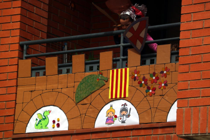 Pla contrapicat d'un nen disfressat de cavaller Sant Jordi al seu balcó engalanat per a la Diada a Tortosa.